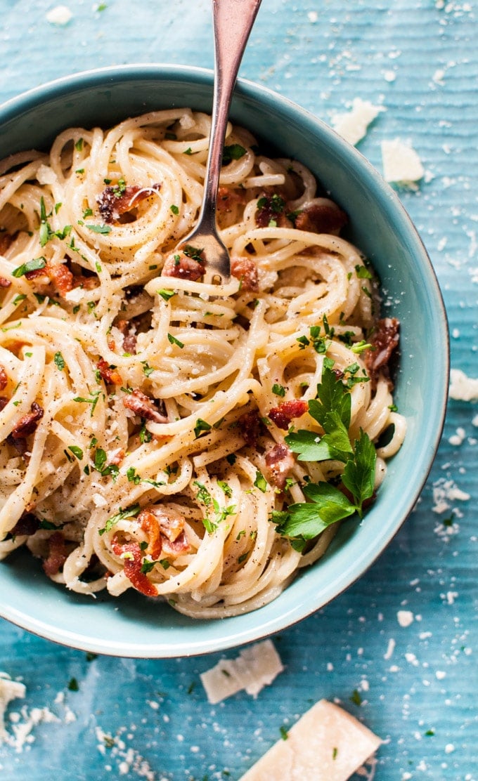 creamy bacon spaghetti in a bowl with a fork and parsley garnish