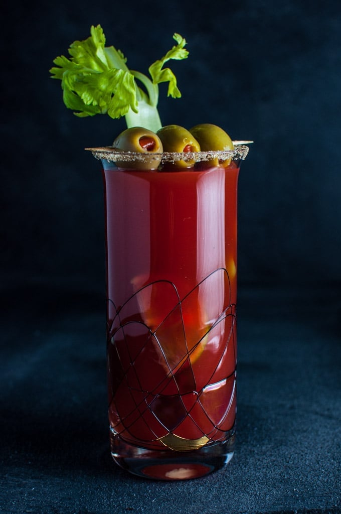 a classic Canadian caesar cocktail in a glass with olives and a celery stick