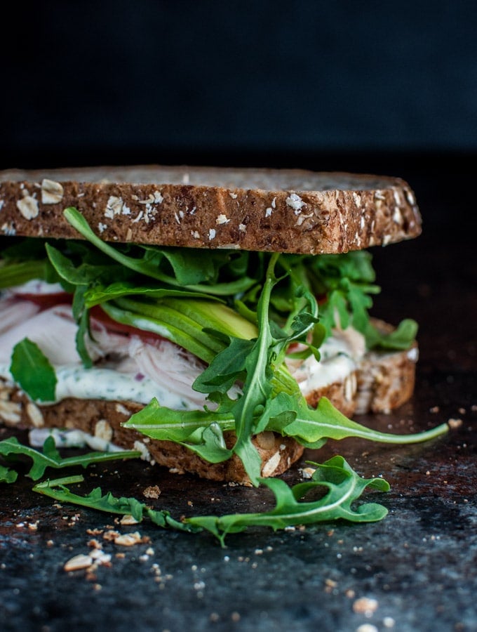 a leftover chicken sandwich with arugula, creamy avocado, herb mayo, tomato, and arugula