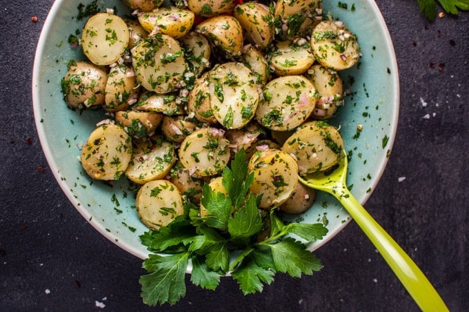 chimichurri potato salad in a bowl with a green serving spoon