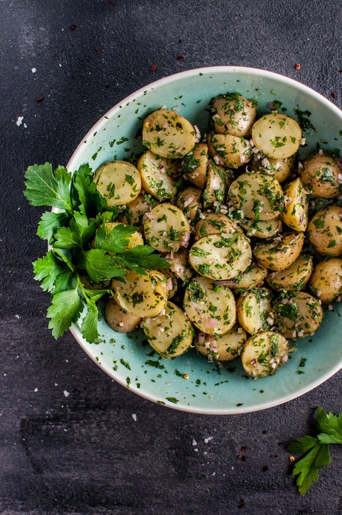 chimichurri potato salad in a teal bowl garnished with parsley