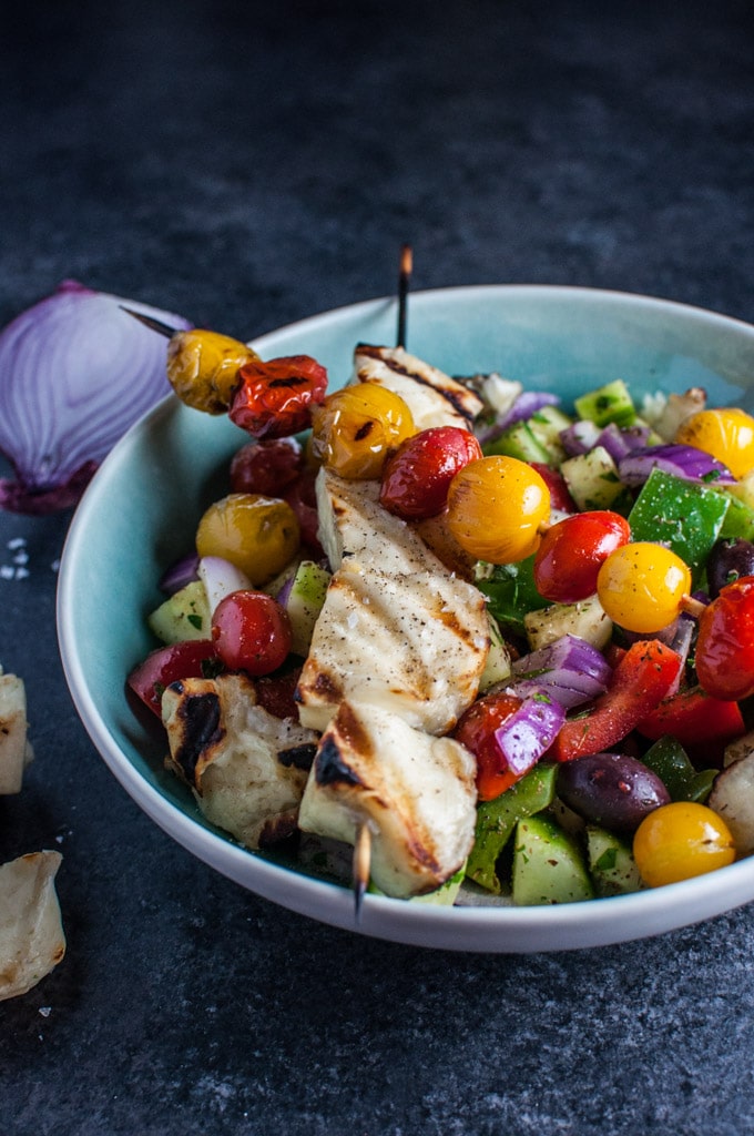 blue bowl with classic Greek salad with grilled halloumi and tomatoes