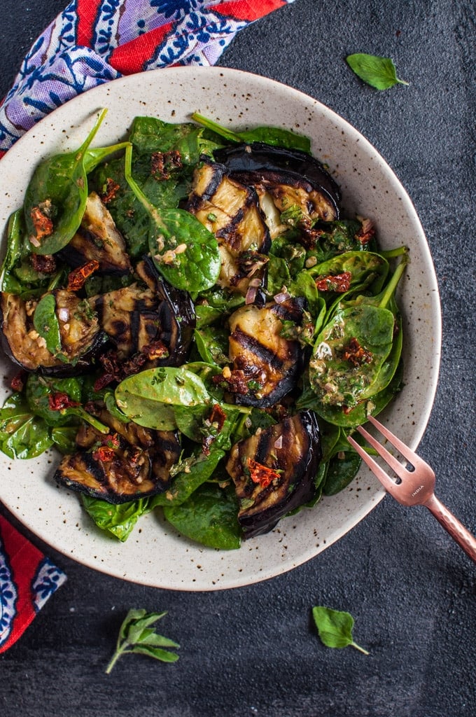 grilled eggplant and spinach salad in a bowl with a fork