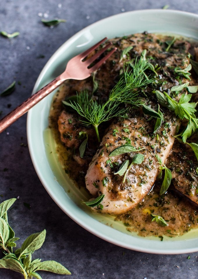 close-up of tilapia fish with a lemon herb butter sauce and a fork