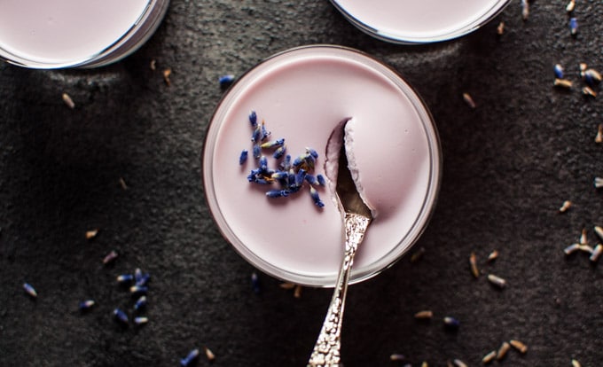 close-up of glass container of lavender panna cotta and a spoon