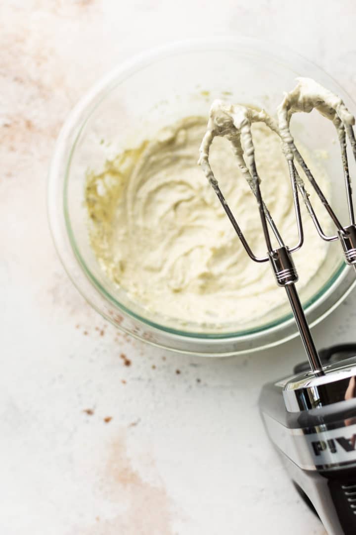 garlic and herb spreadable butter in a glass prep bowl with electric hand mixer