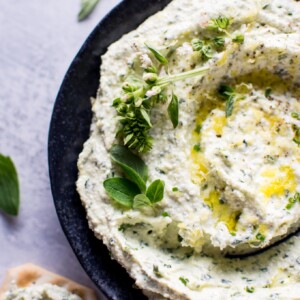 close-up of whipped feta with fresh herbs in a black bowl