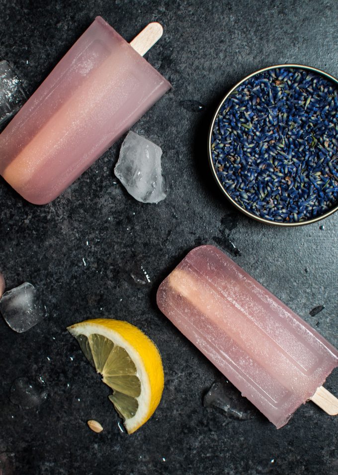 lavender lemonade popsicles next to a tin of lavender and lemon slice