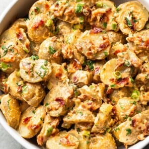 bacon potato salad in a white serving bowl