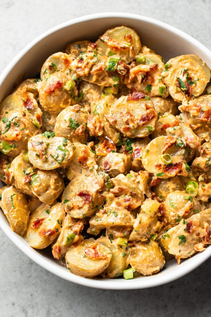 bacon potato salad in a white serving bowl