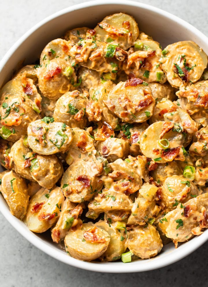 bacon potato salad in a white serving bowl