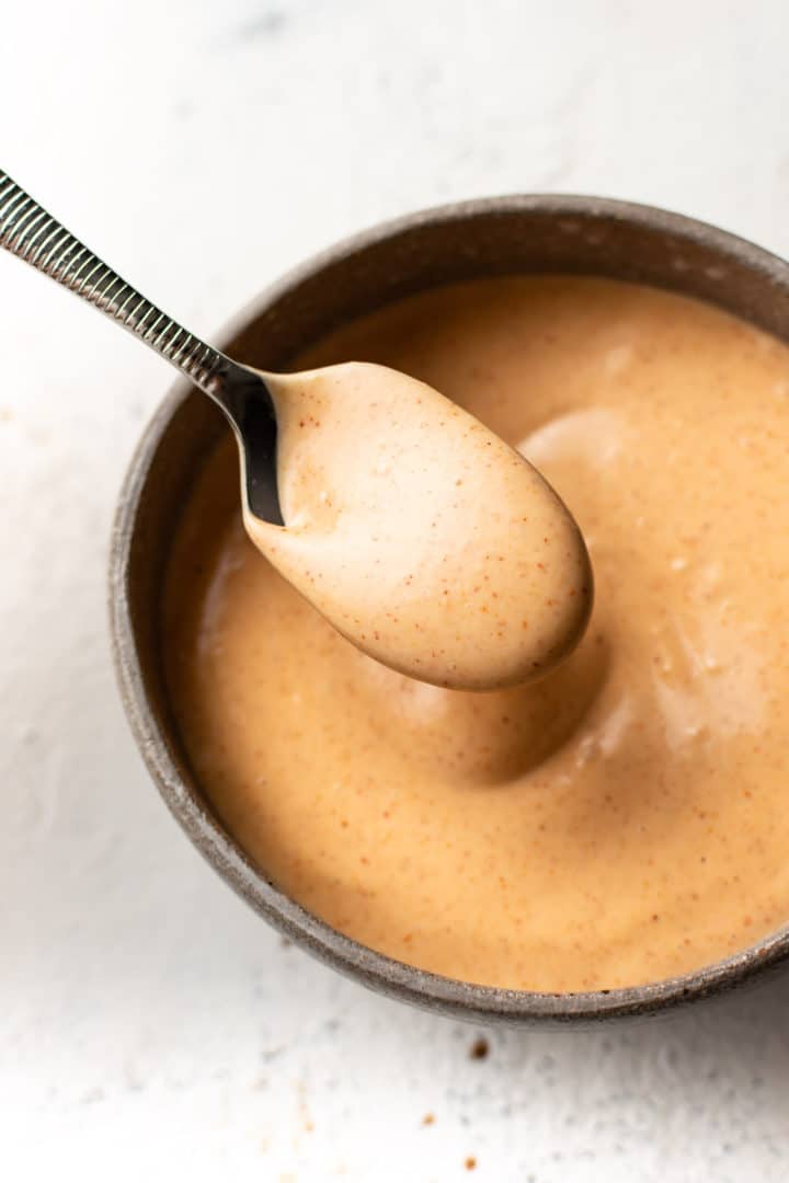 yum yum sauce in a small bowl with a drizzling spoonful of sauce