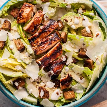 The ultimate summer salad: this caesar salad has tender and smoky BBQ chicken breast, garlic croutons, creamy avocado, oodles of shaved parmesan cheese, and a homemade lemony caesar dressing.