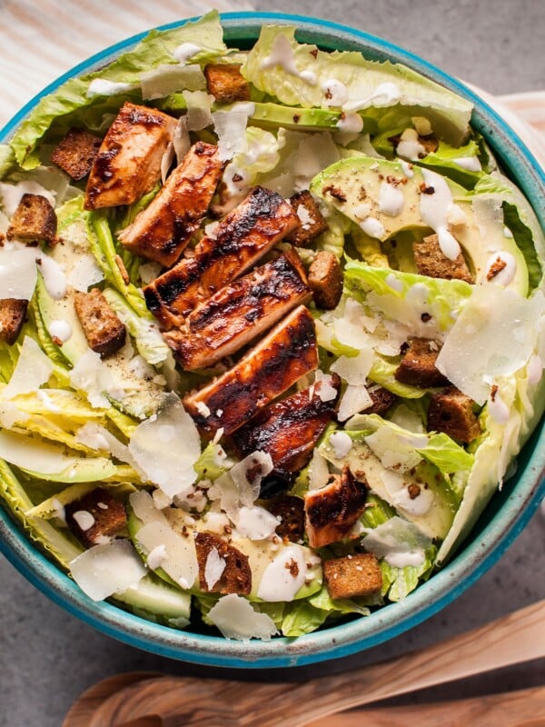 The ultimate summer salad: this caesar salad has tender and smoky BBQ chicken breast, garlic croutons, creamy avocado, oodles of shaved parmesan cheese, and a homemade lemony caesar dressing.