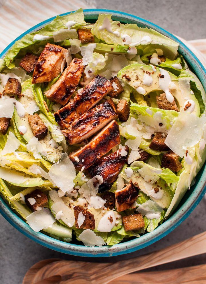 The ultimate summer salad: this caesar salad has tender and smoky BBQ chicken breast, garlic croutons, creamy avocado, oodles of shaved parmesan cheese, and a homemade lemony caesar dressing.