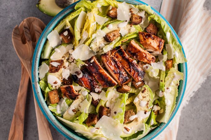 bowl of barbecue chicken salad with creamy homemade Caesar dressing, avocado, and grated parmesan cheese