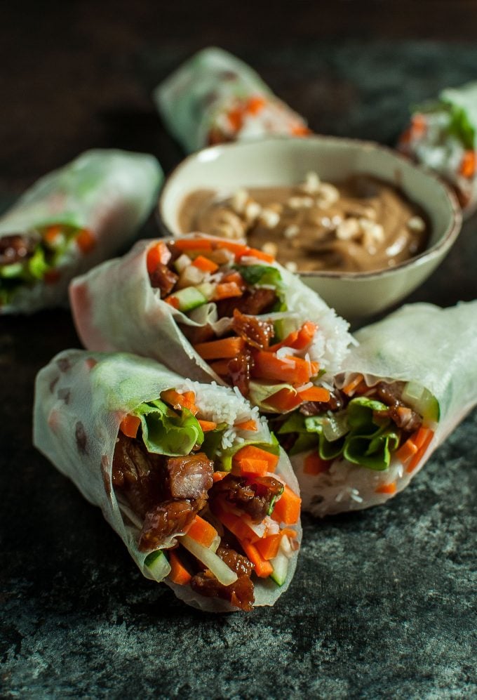 caramelized pork salad rolls next to a small bowl of creamy peanut dip