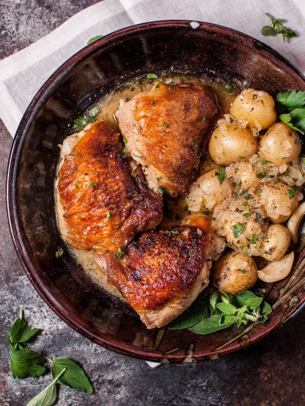 crispy lemon herb chicken with little potatoes in a brown bowl