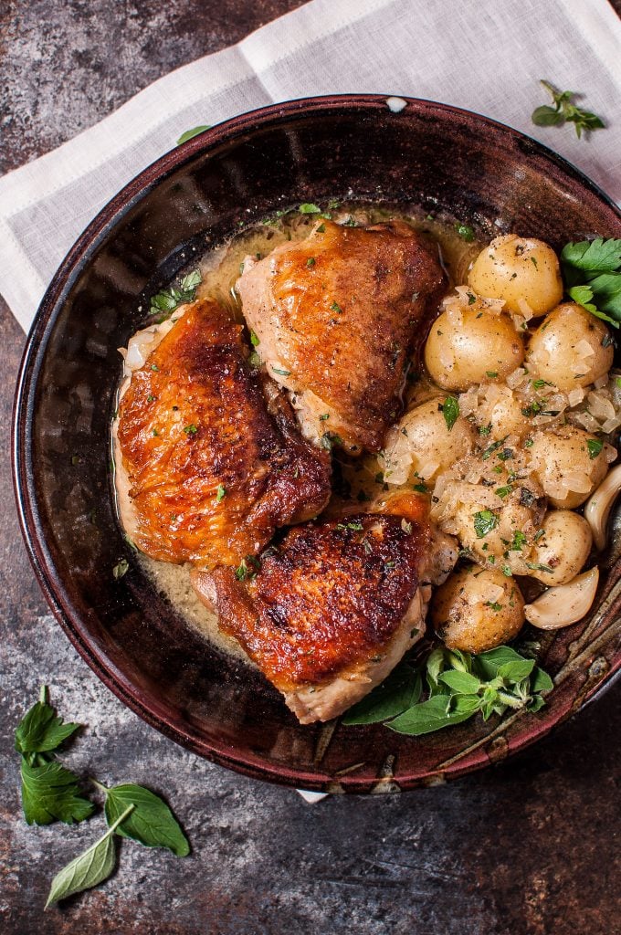 crispy lemon herb chicken and potatoes in a brown bowl