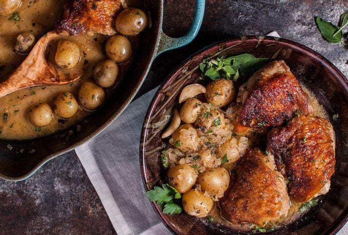 bowl of crispy lemon herb chicken and potatoes next to a skillet