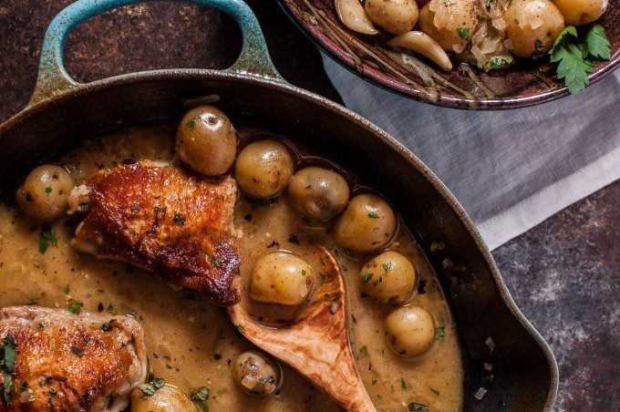 close-up of crispy lemon herb chicken and potatoes with a wooden serving spoon