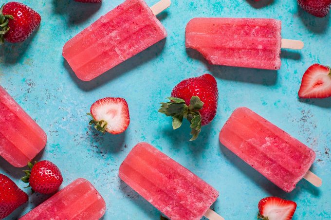 several strawberry moscato popsicles on a flat blue surface
