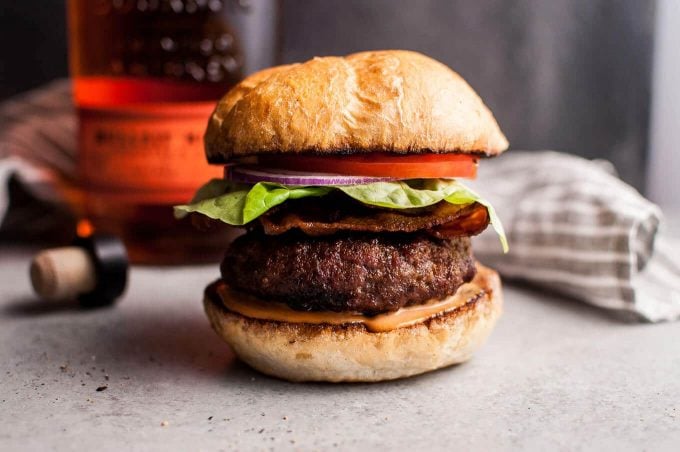 close-up of juicy barbecue bourbon burger with tomato, lettuce, and onion on a bun