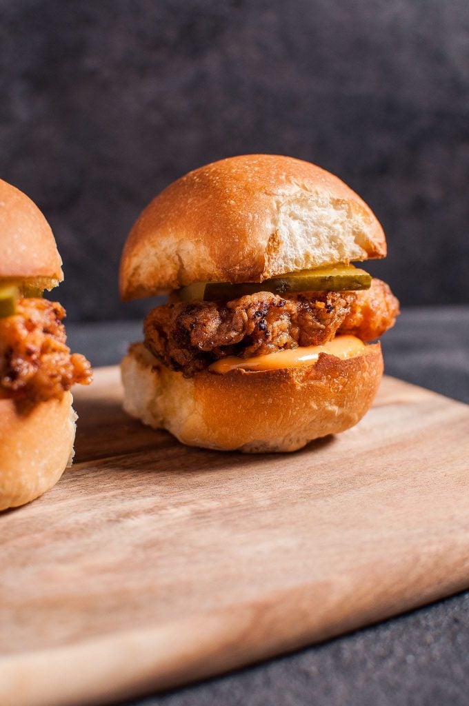 close-up of a fried chicken slider with spicy mayo on a wooden cutting board