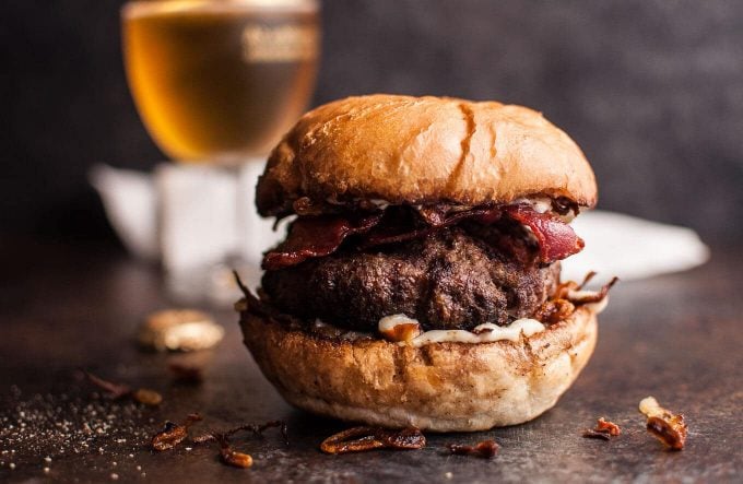 close-up of a beef burger with bacon, horseradish mayo, and fried onions