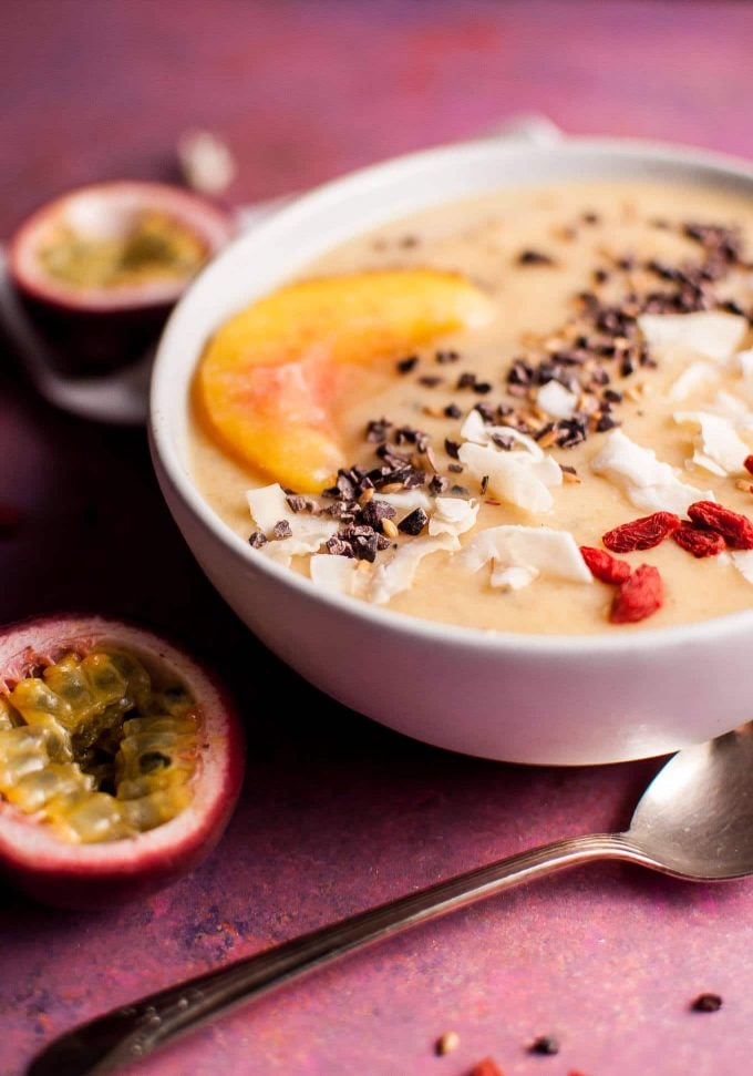 close-up of passion fruit and peach smoothie bowl next to spoon
