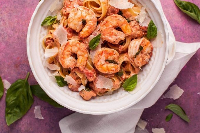 bowl of rosé pasta with shrimp next to a white cloth napkin