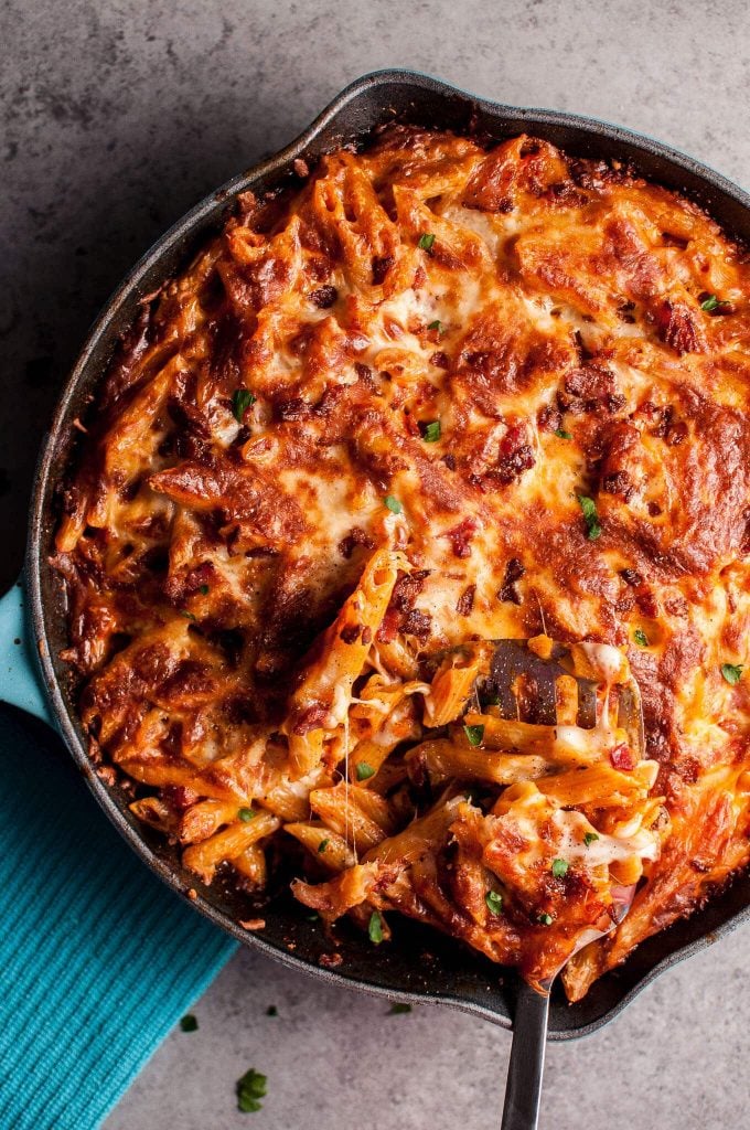 one-pan cheesy bacon penne in a skillet with a metal serving spatula