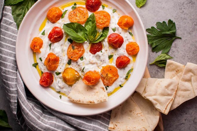 bowl of summer Greek yogurt dip with roasted little tomatoes appetizer and pita bread slices