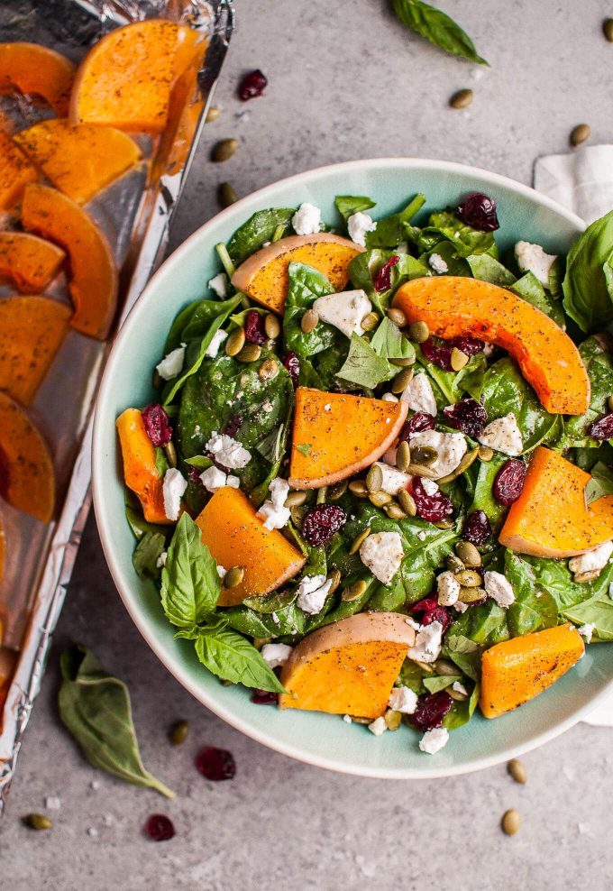 teal bowl of butternut squash and spinach salad with goat\'s cheese