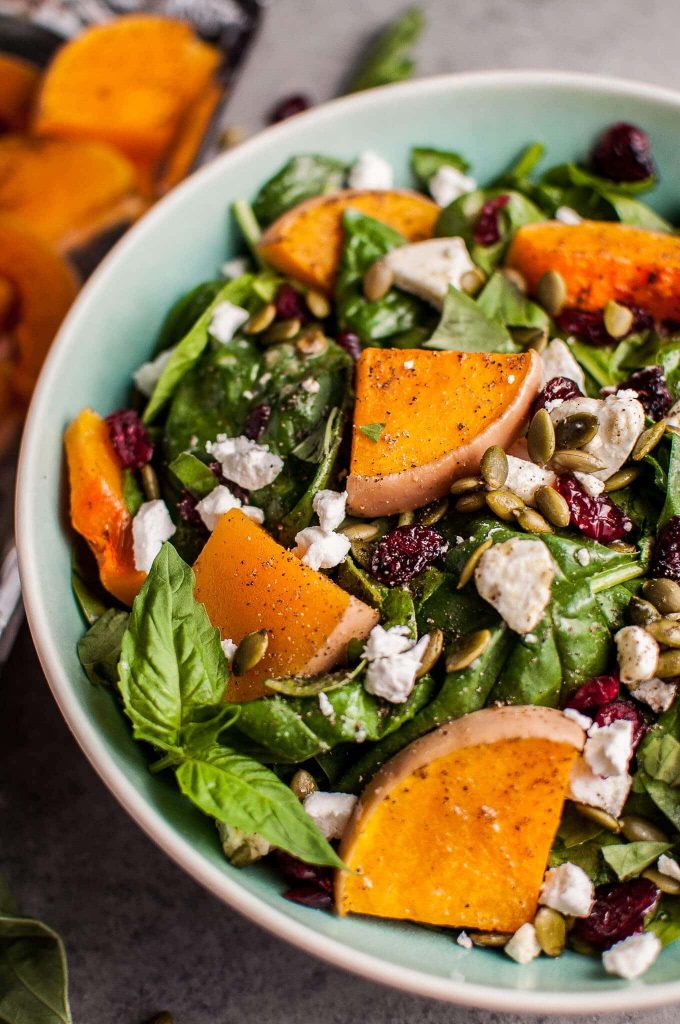 close-up of butternut squash and spinach salad with goat cheese in a bowl
