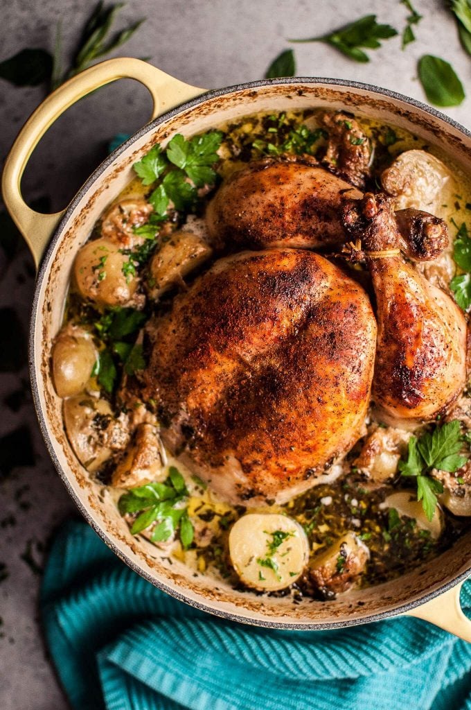 creamy lemon and herb roasted whole chicken in a pot with little potatoes