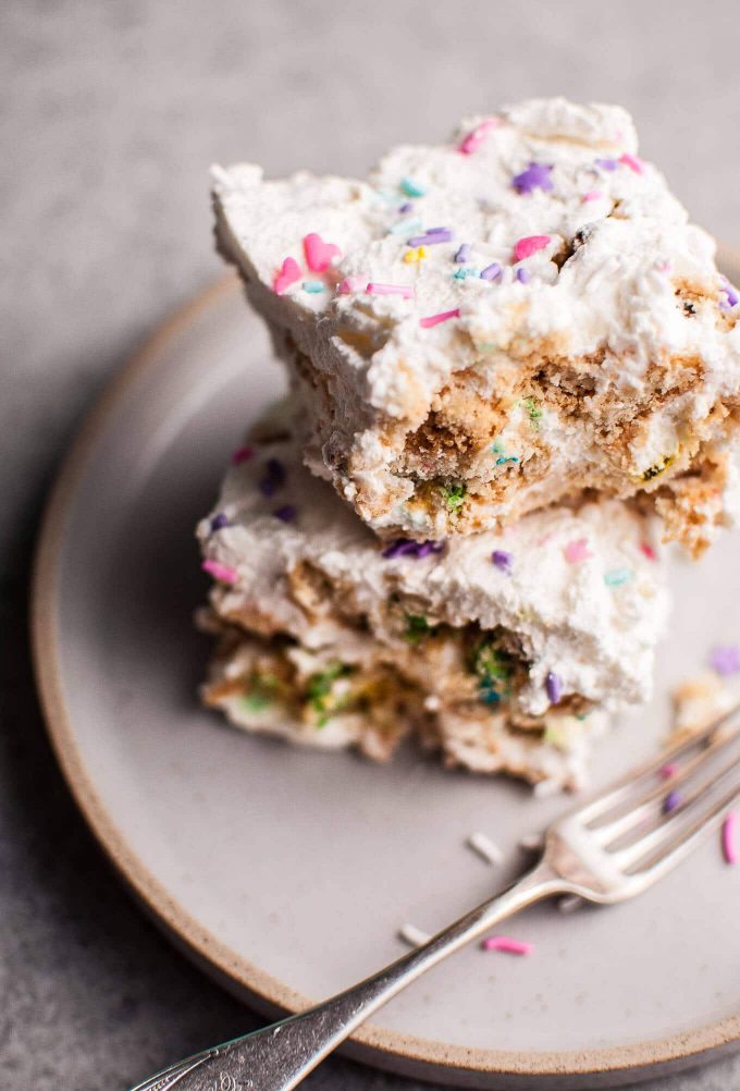 close-up of two pieces of rainbow icebox cake on a plate with a fork