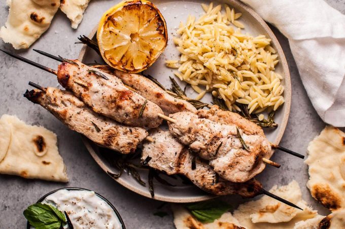 close-up of plate with charred lemon, orzo, and rosemary chicken skewers