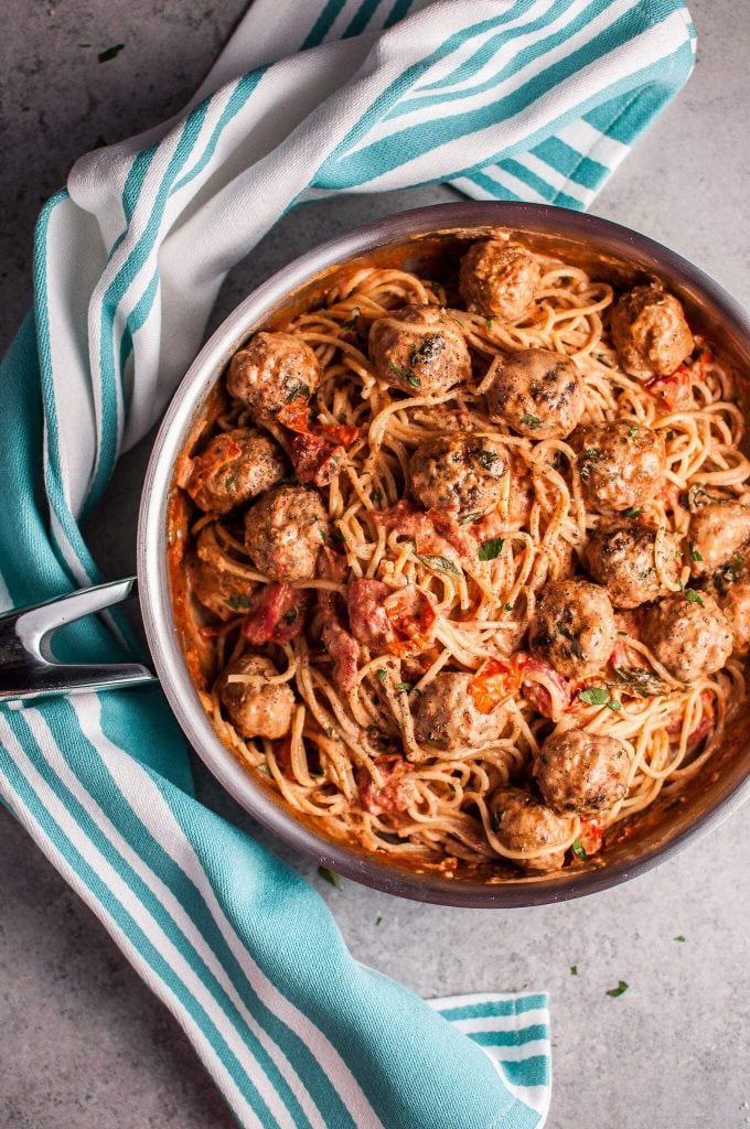 sausage meatball pasta with roasted tomatoes in a metal skillet