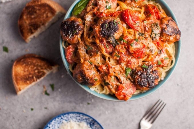 close-up of sausage meatball pasta with roasted tomatoes in a bowl and a fork