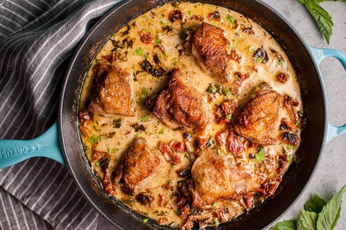 skillet with crispy chicken in a creamy sun-dried tomato and basil sauce