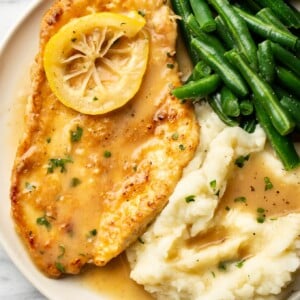 a plate with chicken francese, green beans, and mashed potatoes
