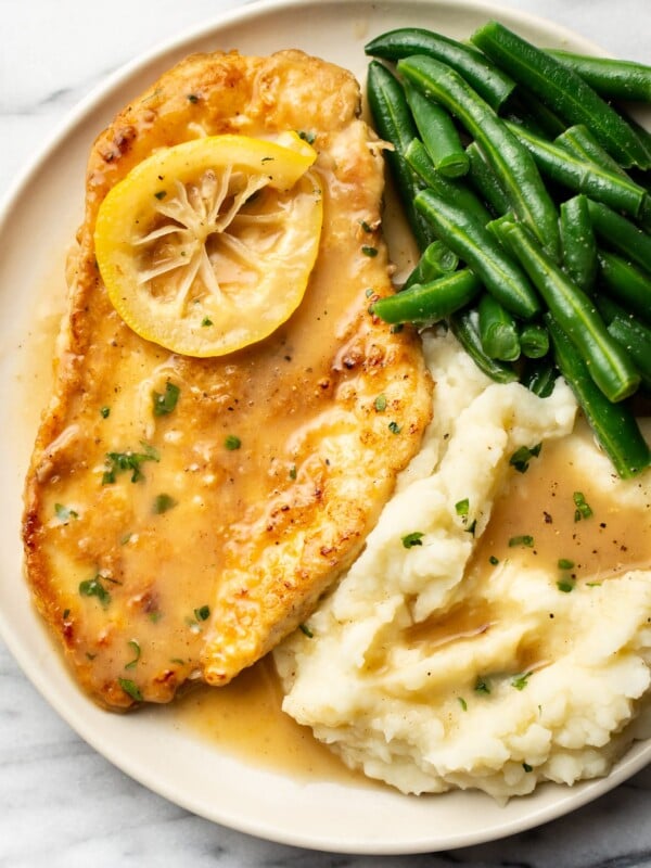 a plate with chicken francese, green beans, and mashed potatoes