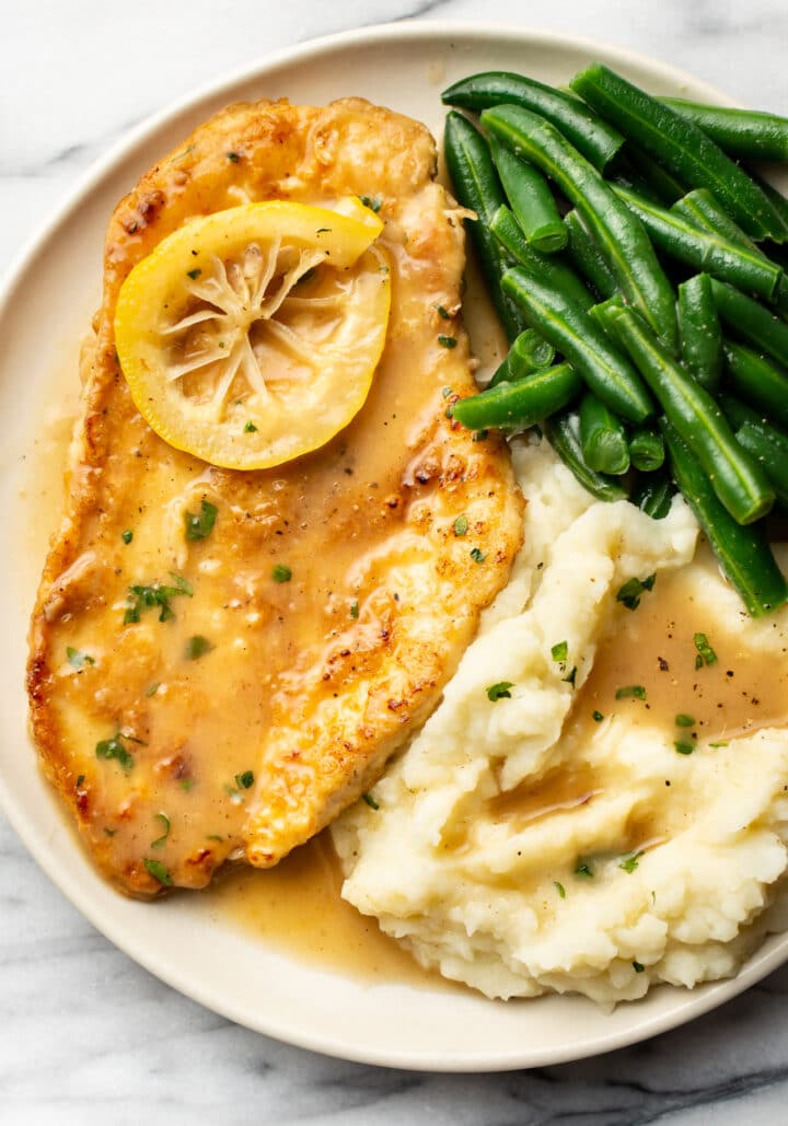 a plate with chicken francese, green beans, and mashed potatoes