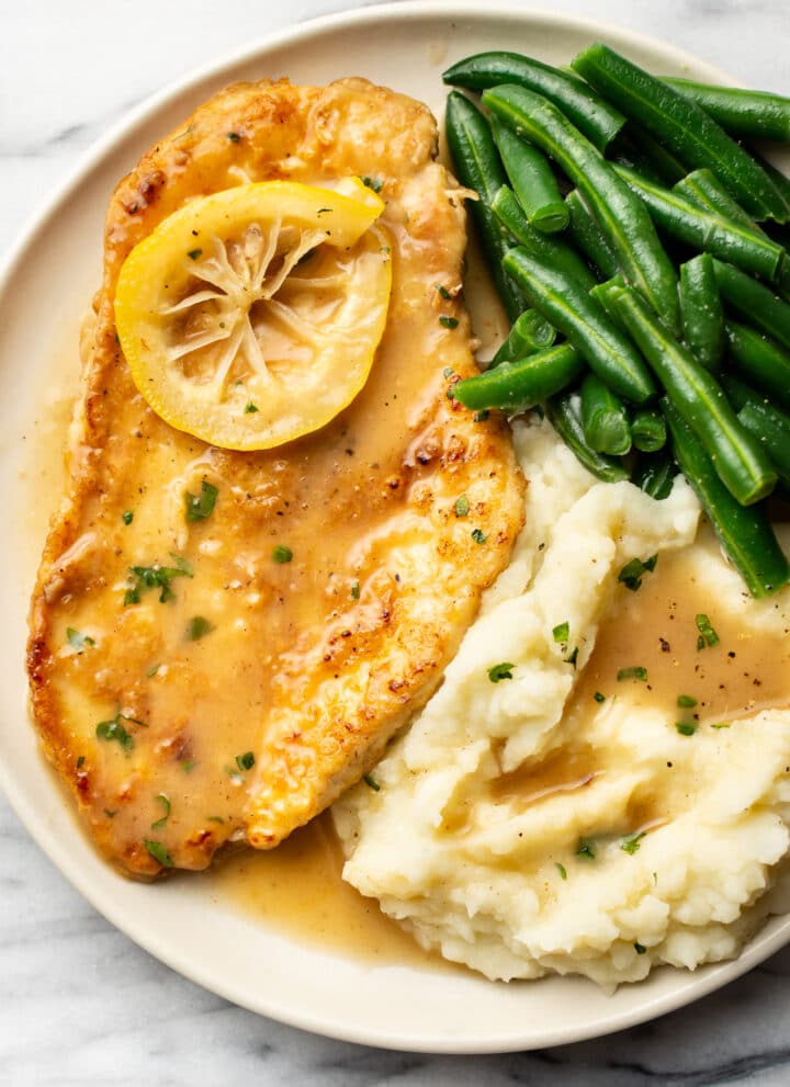 a plate with chicken francese, green beans, and mashed potatoes