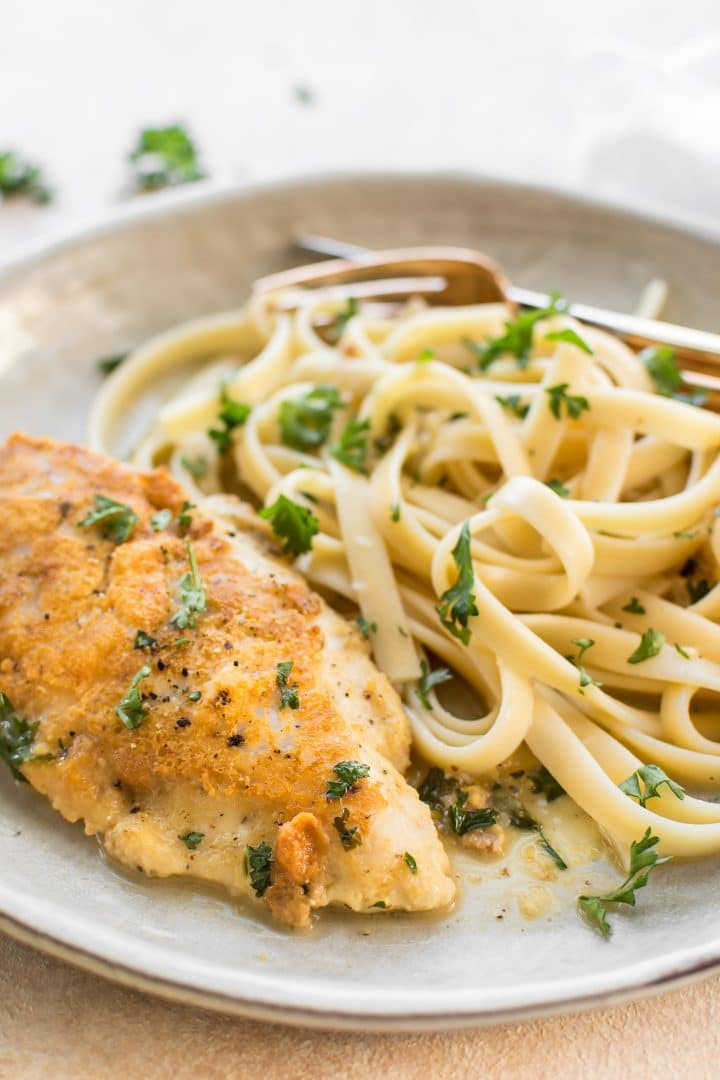 easy chicken Francese on a plate with pasta and parsley garnish