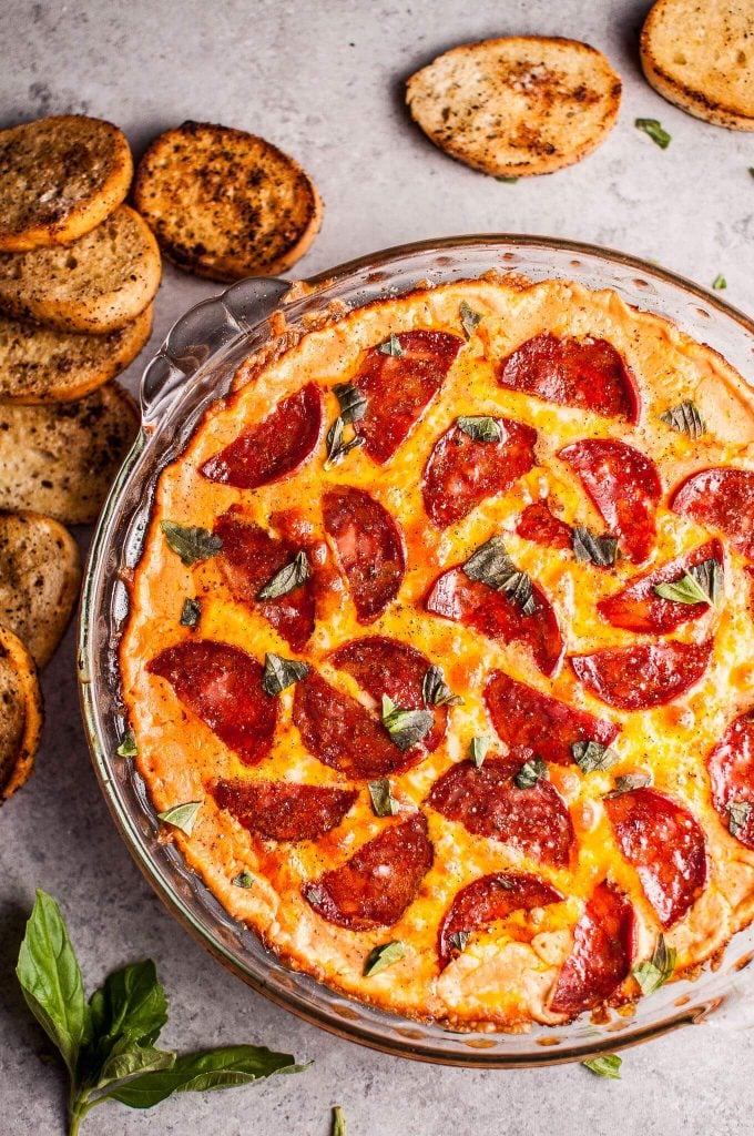 glass dish with chorizo pizza dip and toasted garlic bread slices