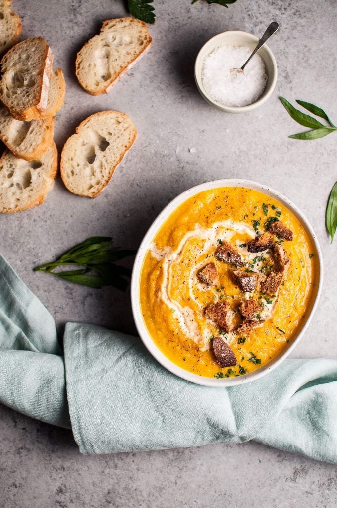 pumpkin and cauliflower soup with ginger next to baguette slices and cloth napkin