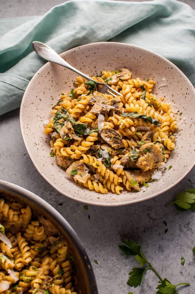 bowl of pumpkin, mushroom, and spinach pasta with a fork