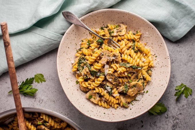 bowl of healthy pumpkin, mushroom, and spinach pasta with a fork